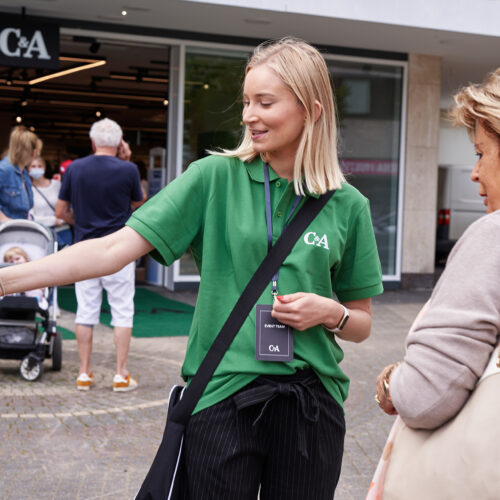 Eine Mitarbeiterin von C&A erklärt einer Person etwas bei der Neueröffnung einer Filiale