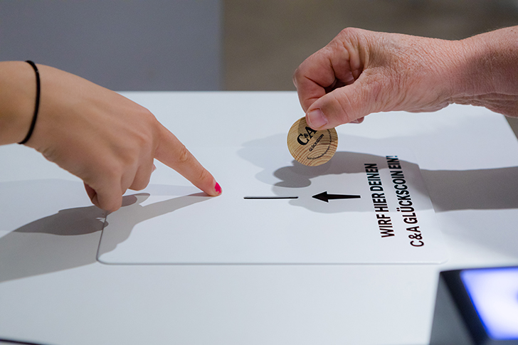 Einwurf einer Münze bei der Coin and Win Aktion bei der Neueröffnung von einer C&A Filiale