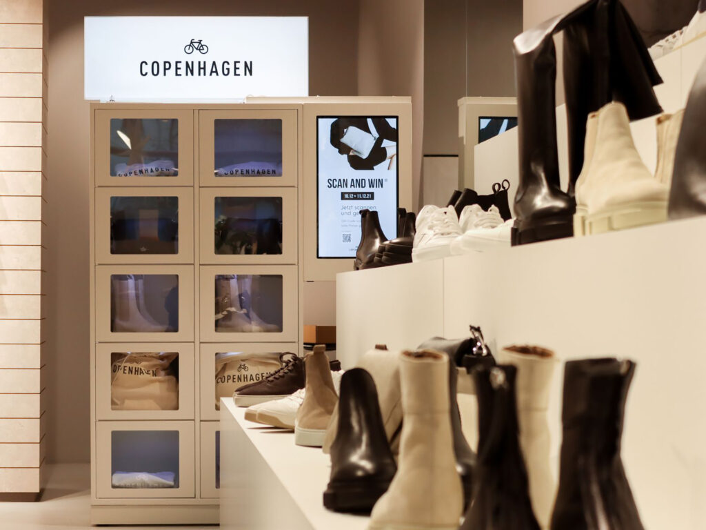 Hinter einer Reihe von Schuhen ist die gefüllte Gewinn-Vitrine LOWIMA zu sehen